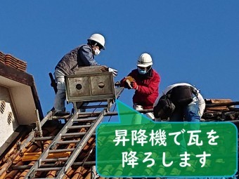 岩出市で屋根の葺き替え工事を行うのにセメント瓦を剥がし昇降機へ瓦を乗せて降ろしていきます